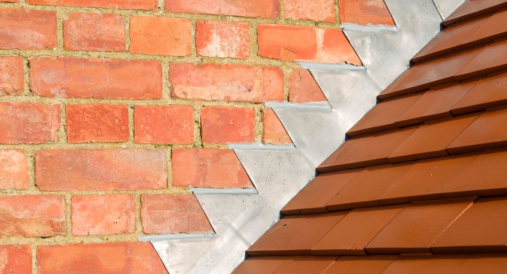 Closeup of new plain red clay tiles and lead flashing on a pitched roof