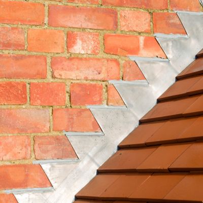 Closeup of new plain red clay tiles and lead flashing on a pitched roof